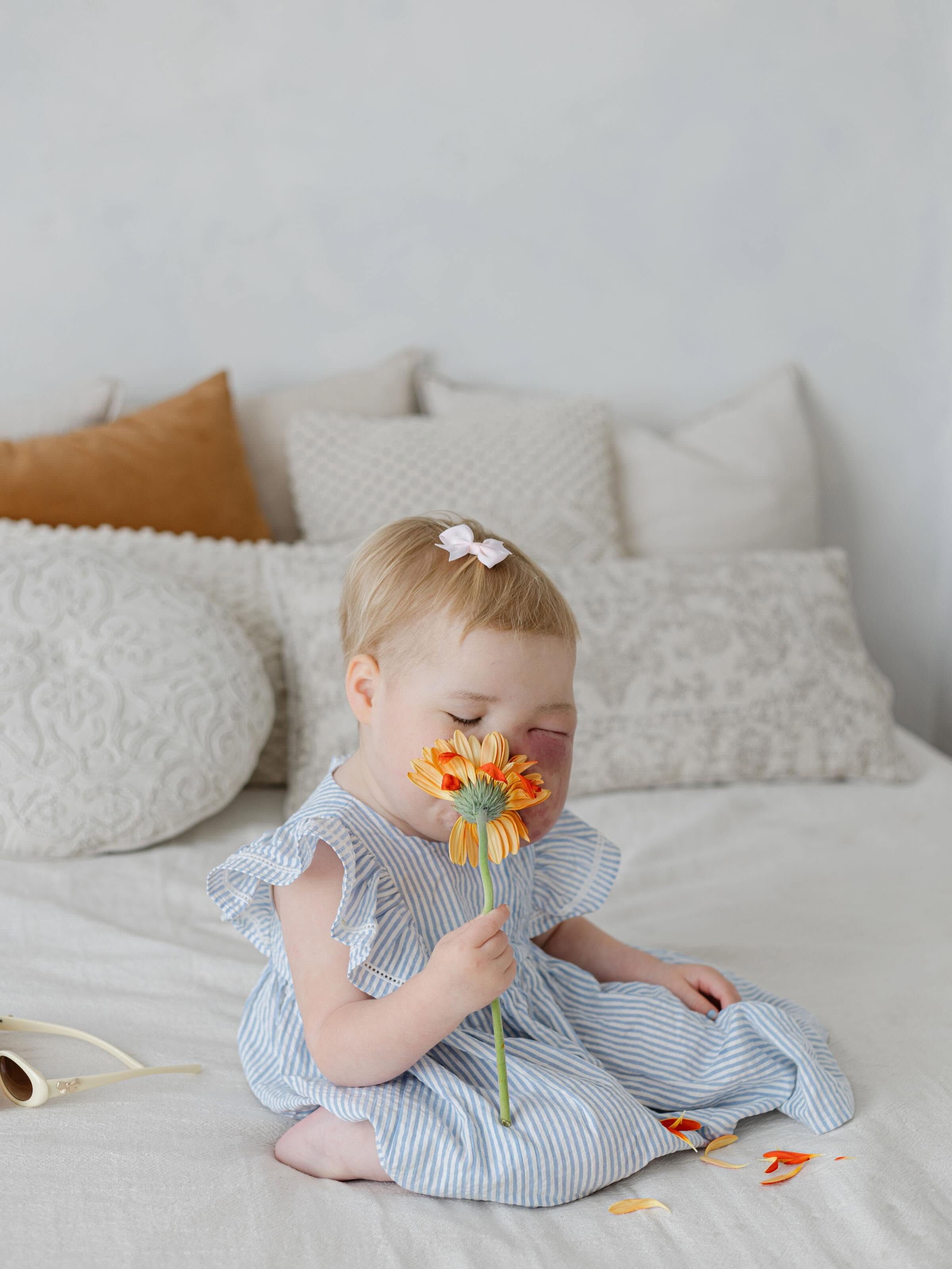 Myla sitting with an orange flower